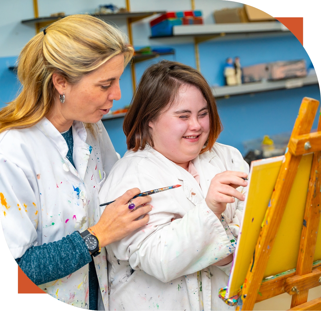 Woman assisting girl painting on canvas.